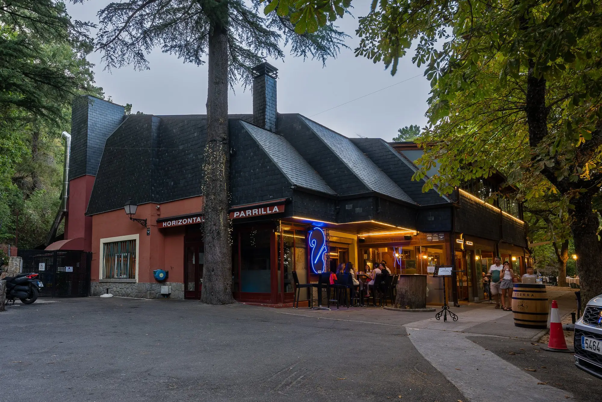 La fachada de Restaurante Horizontal al anochecer, con los rótulos «Horizontal» y «Parrilla» y la ardilla de neón azul