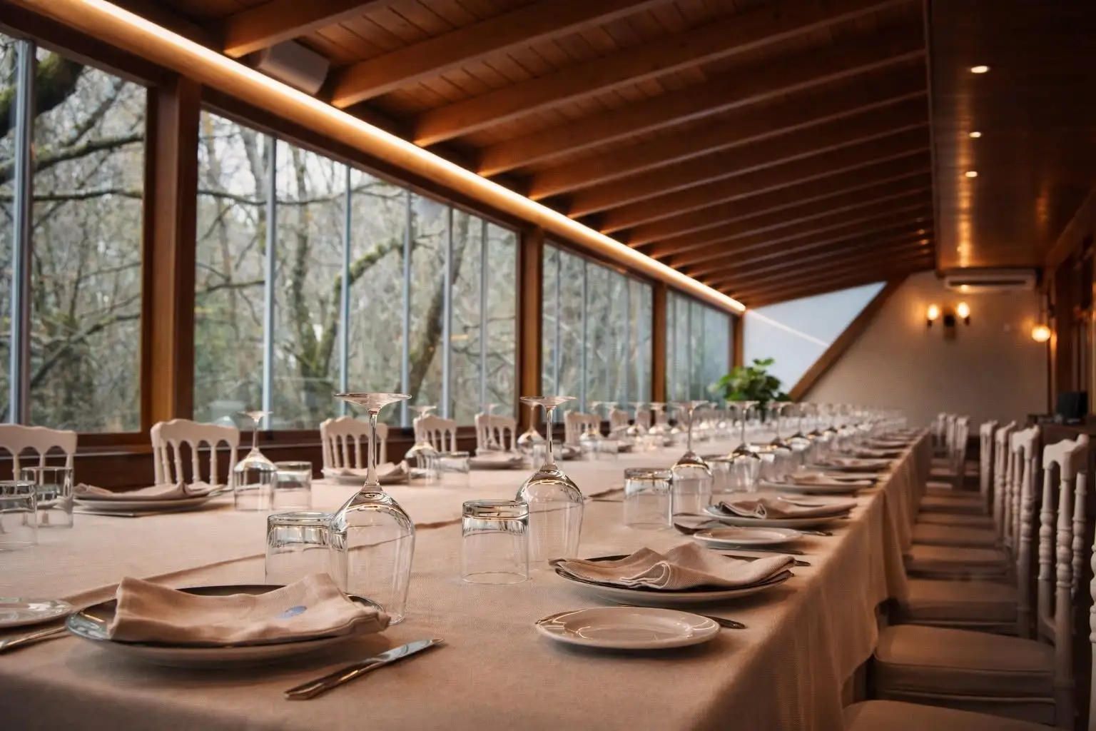 Mesa imperial montada en el comedor acristalado de día, con los ventanales a todo lo largo