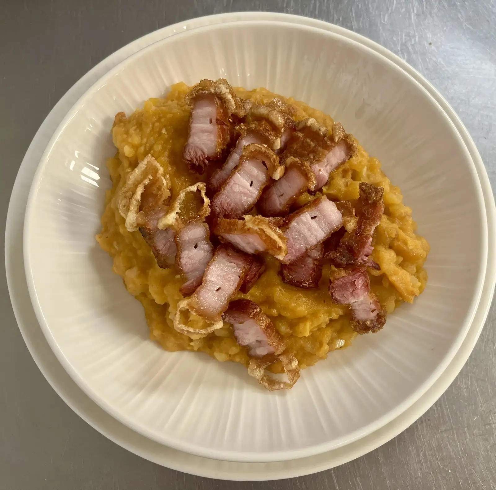 Patatas revolconas con torreznos crujientes y cebolla frita por encima